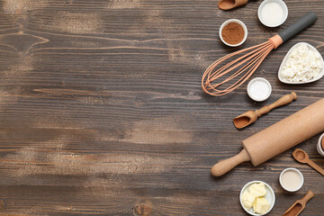 Different ingredients for preparing sweet cinnamon roll on wooden background