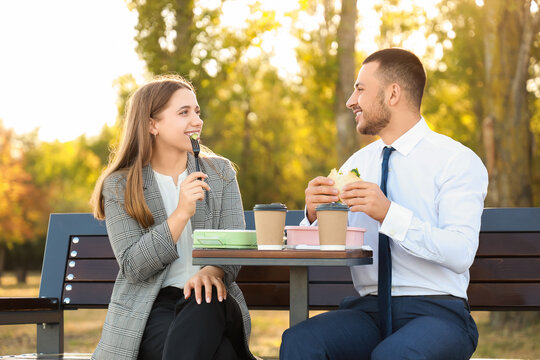 Business colleagues having lunch on bench in park