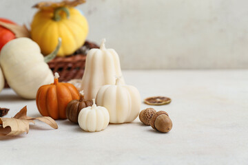 Composition with autumn candles, pumpkins and acorns on light table