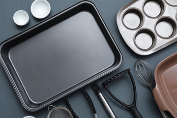 Baking tray with kitchen utensils on black background. Top view