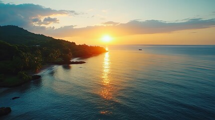 Fototapeta premium Sunset reflecting on calm waters at a tropical beach with lush greenery and distant hills in the background