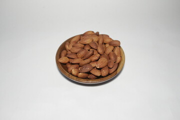 Almonds on a wooden plate with a white background