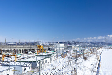 Obraz premium 冬の青空と積雪をバックに走る東北本線（利府）