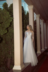 Fototapeta premium beautiful blonde bride posing in open gallery of hotel. in long wedding dress
