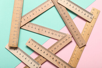 Wooden rulers on color background