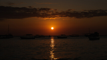 Fototapeta premium Boats floating on calm ocean water during golden hour sunset in zanzibar, tanzania