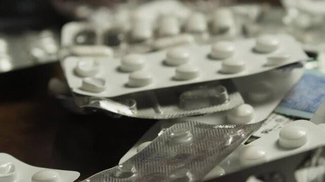 Anxious hand sifts through blister packs, searching for medication CLOSE-UP