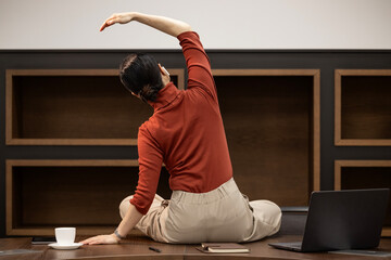 Yoga and breathing exercise at work. Calm Japanese woman sitting on desk in the office and doing...