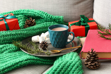 Books with cocoa, Christmas gifts and warm sweater on sofa, closeup
