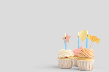 Sweet Birthday cupcakes with burning candles on grey background
