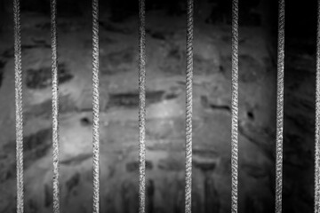 Gray prison bars against a blurred backdrop of barren land at dusk evoke feelings of isolation and...