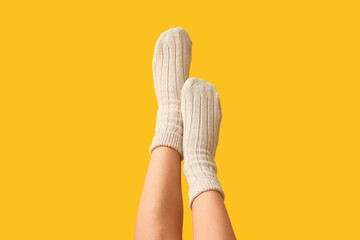 Legs of young woman in cotton socks on yellow background