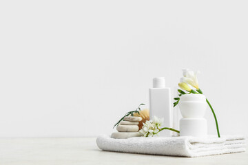Composition with cosmetic products, spa accessories and flowers on light background