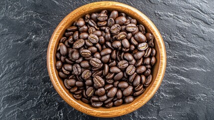 Fototapeta premium Top-down view of a wooden bowl holding aromatic coffee beans, placed on a dark background with empty copy space.