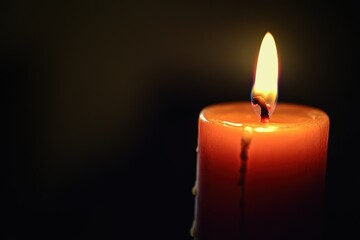 Close-up of a burning candle illuminating a dark room with a warm glow and soft shadows at night