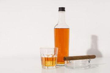 Bottle and glass of rum with cigar on white background