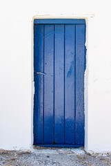 Exterior vertical blue door, on white wall.