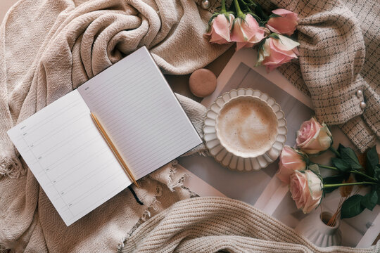 Flat lay of an open weekly planner with a pen, coffee cup, pink roses, and cozy neutral fabrics. Ideal for planning, journaling, or productivity lifestyle themes with a soft feminine aesthetic