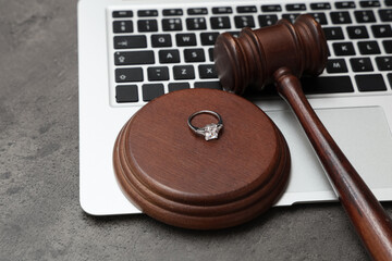 Auction gavel with ring and laptop on dark background, closeup