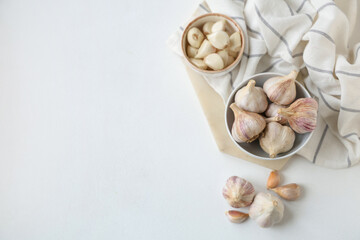 Bowls with fresh garlic and cloves on white background