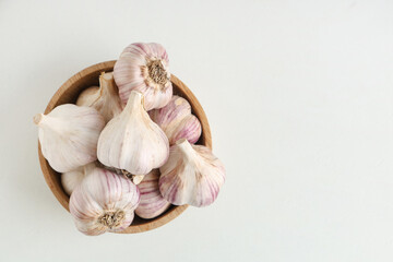 Wooden bowl with fresh garlic on white background
