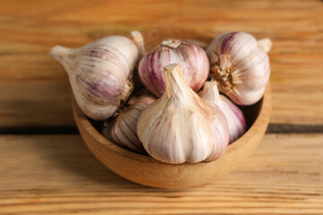 Bowl with fresh garlic on wooden background