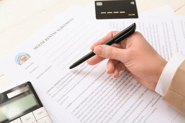 Woman filling out house rental agreement on white wooden background, closeup
