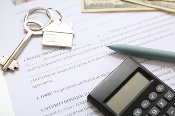 Key with calculator on house rental agreement, closeup