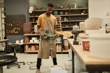 African potter using a mixer in a large ceramics workshop