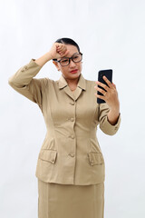 Stressed Indonesian civil servant woman holding cell phone while having headache
