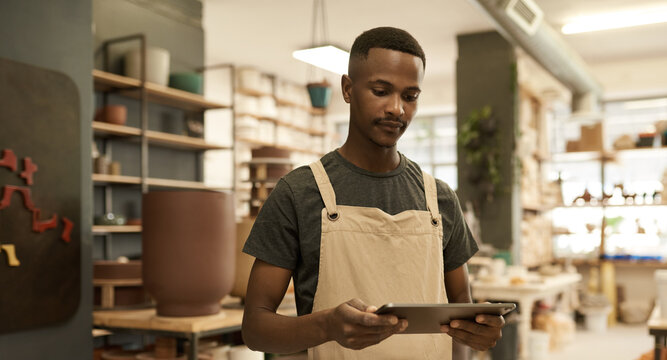 Young African pottery studio manager working on a digital tablet