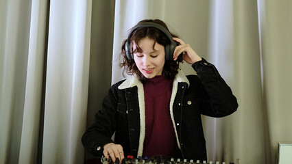 A girl adjusts a sound mixer while singing, her headphones emphasizing the focus on audio. The photo captures the joy of engaging in creative and musical tasks.