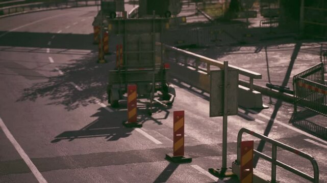 A roadblock is set up on a quiet street, restricting vehicle access due to ongoing construction work. Traffic cones and barriers indicate detours and safety precautions.
