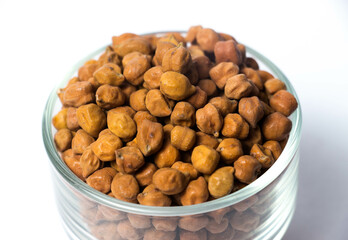 Closeup shot of Organic Brown Chickpeas in a Glass Bowl Isolated on a white background. Black chickpeas, also known as kala chana, Bengal gram,Egyptian pea.