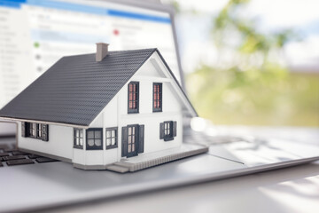 Model house on laptop searching the internet for real estate or new house