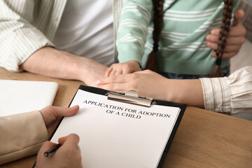 Couple adopting girl with social worker at table in office, closeup
