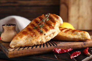 Boards with tasty grilled chicken breast, thyme, dried chilli peppers and peppercorns on wooden background