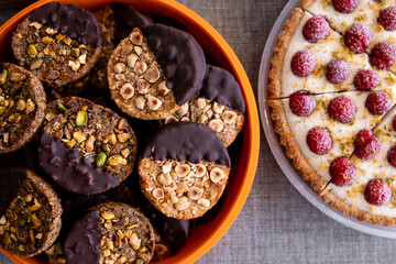 Assorted cookies with nuts and chocolate dipped sections next to raspberry tart