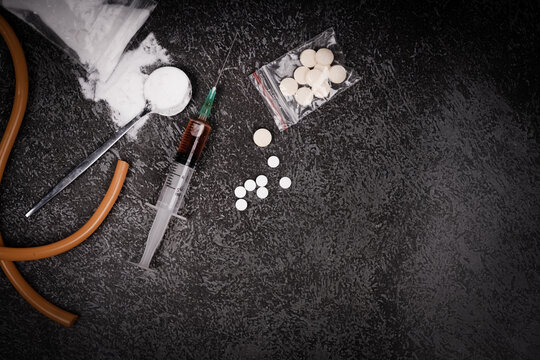 Syringe with drugs dose and medical tourniquet on black background. Narcotic substances in spoon. powder in plastic bag. Drugs concept on dark place. Heroin narcotic crime. Danger addict criminal