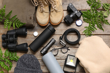 Composition with different travel items, shoes, clothes and fern leaves on wooden background