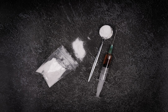 Syringe with drugs dose on black background. Narcotic substances in spoon. powder in plastic bag. Drugs concept on dark place. Heroin narcotic crime. Danger addict problem criminal