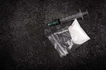 Syringe with drugs dose on black background. powder in plastic bag. Drugs concept on dark place....