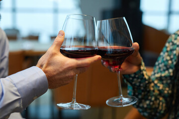 Close-up of couple toasting with glasses of red wine in the restaurant