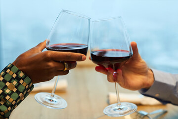 Close-up of diverse couple toasting with glasses of wine and celebrating in the restaurant