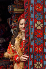 Obraz premium Asian girl in national Slavic dress against the background of carpets. Maslenitsa