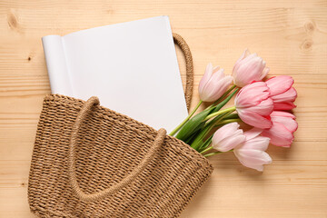 Wicker basket with blank fashion magazine and tulip flowers on wooden background. Spring season concept