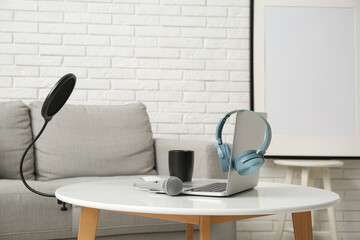 Laptop with headphones and microphone on table in recording studio