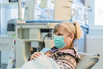 Woman holding premature baby during kangaroo care in NICU