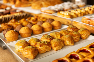 Variety of baked pastries, muffins and sweet rolls displayed on buffet table in cozy bakery or cafe setting for Breakfast, Brunch and Dessert Lovers Savoring Sweet and Savory Treats