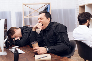 The security guard who sits in front of the monitor yawns.